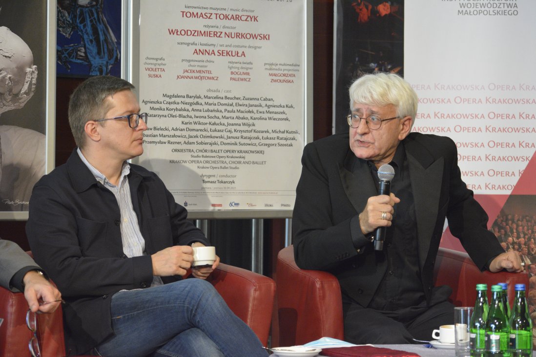 Włodzimierz Nurkowski, reżyser, wypowiada się do mikrofonu. Po lewej Tomasz Tokarczyk,  trzyma filiżankę kawy.