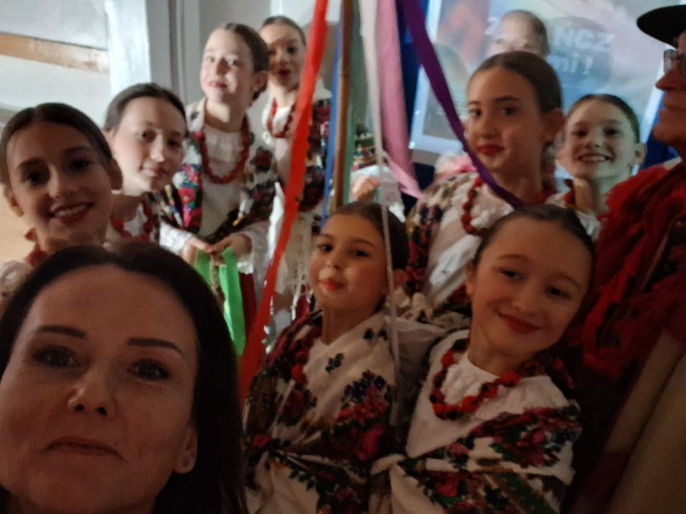 Usmiechnięte dziewczynki w góralskich strojach ludowych pozują do zdjęcia.